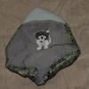 A painting of a dog on a rock suface, painted on a rock